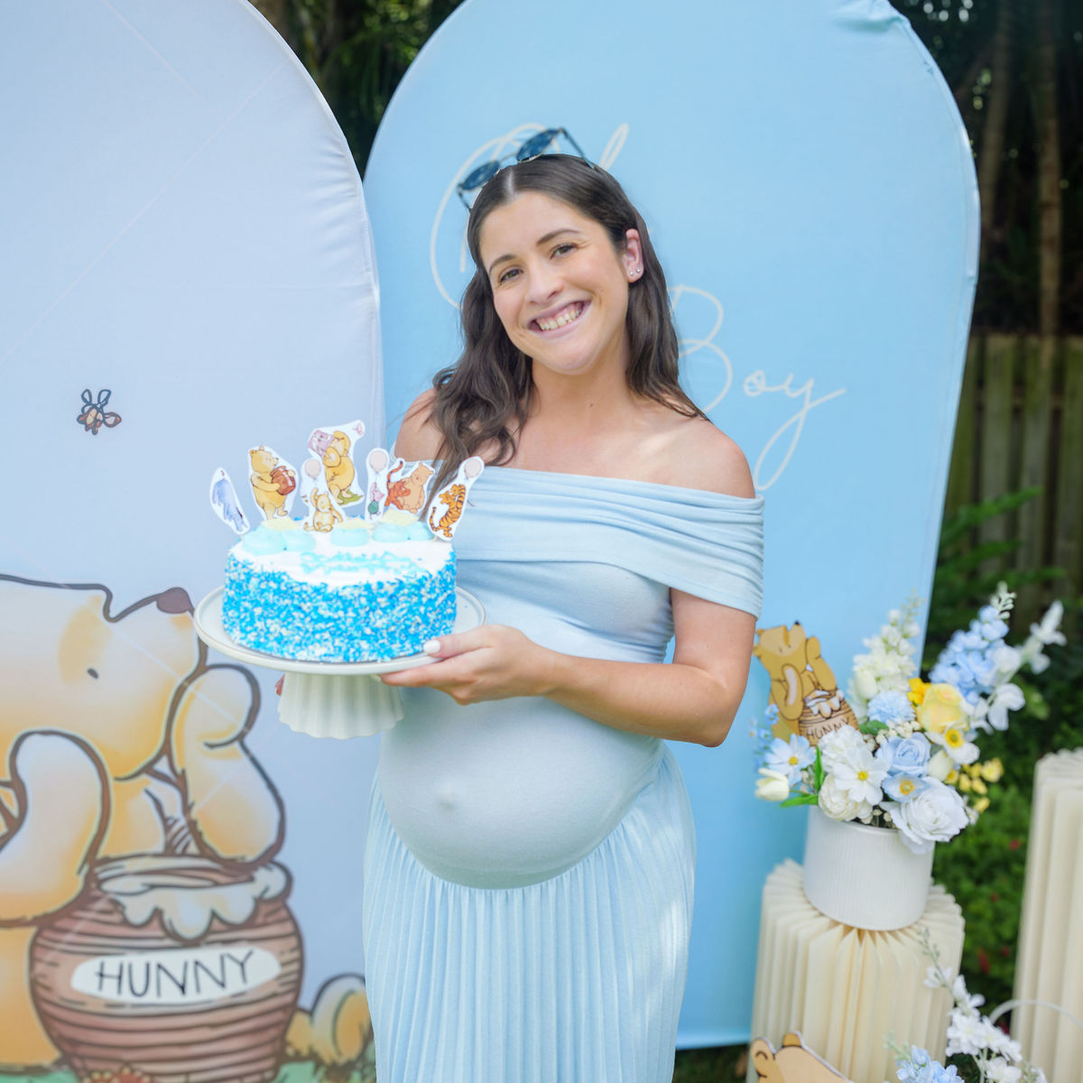 Winnie the Pooh themed baby shower styled with a blue arch backdrop, silk florals and balloons