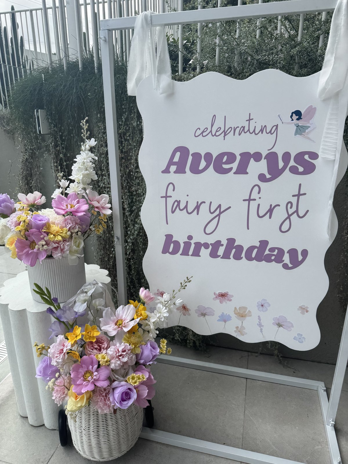 Fairy themed birthday table styled with a personalised sign, pastel silk florals and balloons